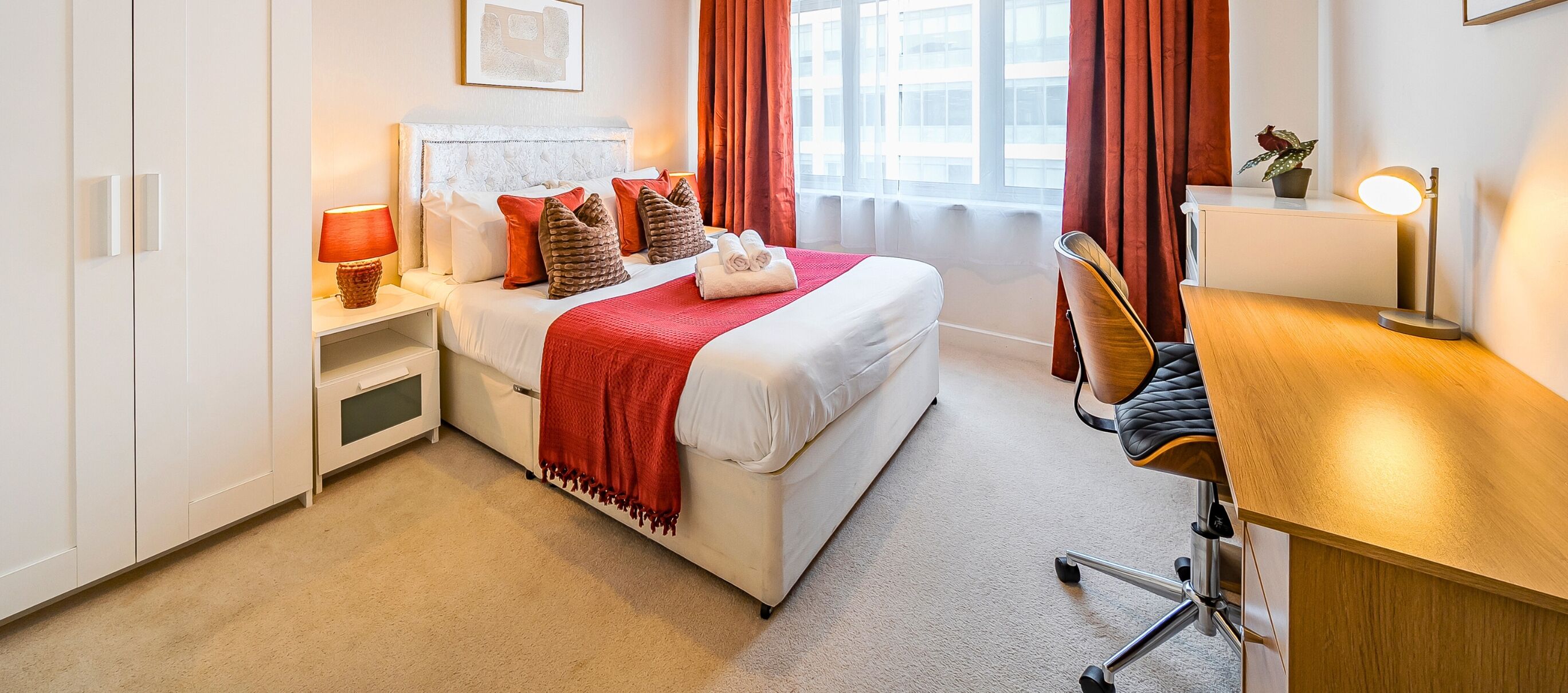Een hotelkamer met een bed, nachtkastjes, een bureau en een stoel.