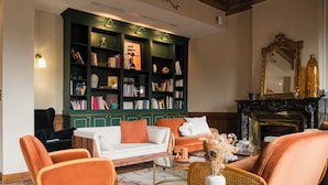 Una sala de estar acogedora con una estantería verde, una chimenea y asientos cómodos.