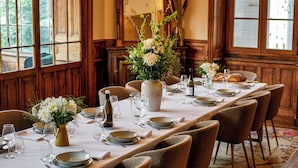 Comedor con una larga mesa dispuesta para una comida, paredes con paneles de madera y lámparas colgantes.