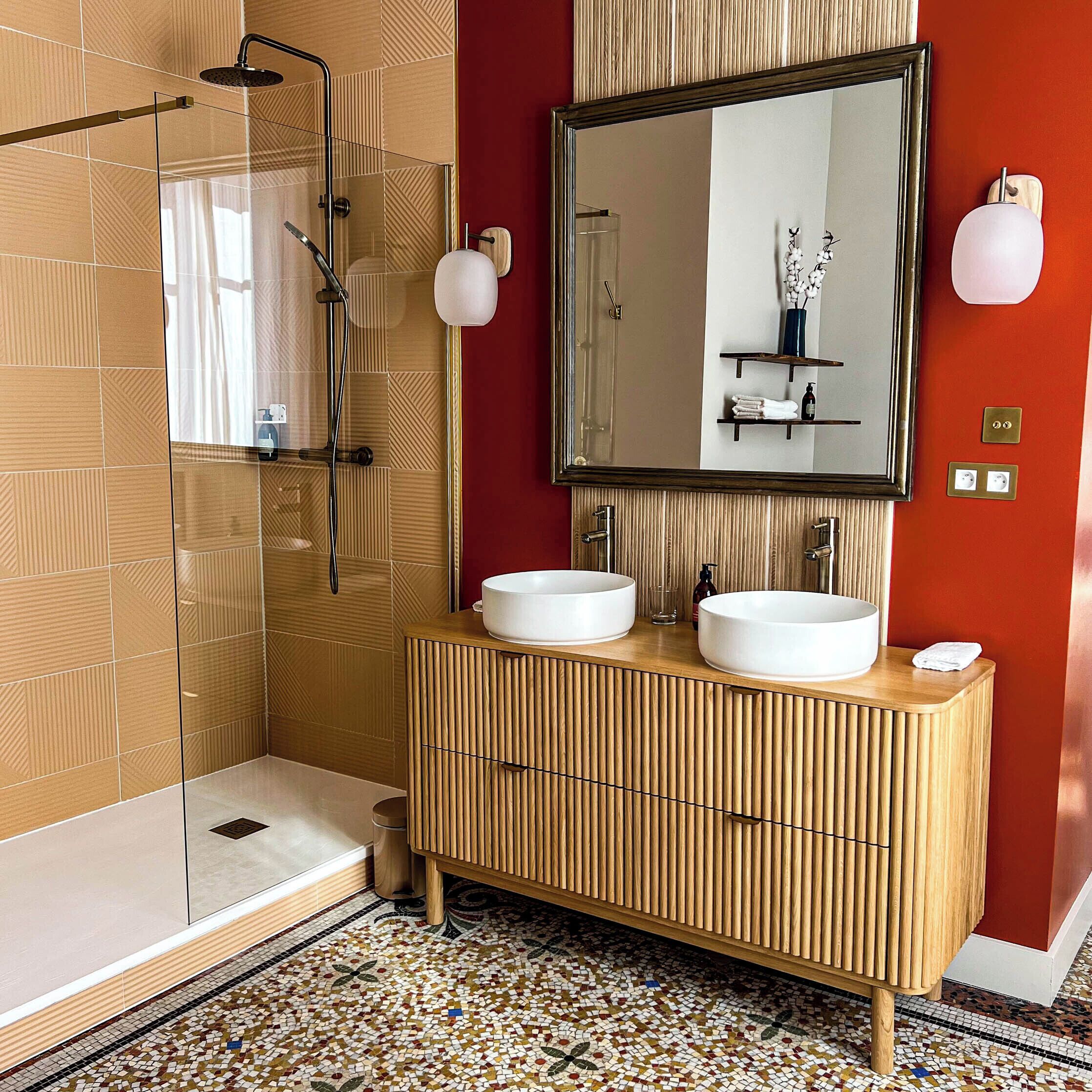 Ein modernes Badezimmer mit Duschkabine aus Glas, zwei Waschbecken, einem großen Spiegel und einer Holzwaschtischunterschrank.