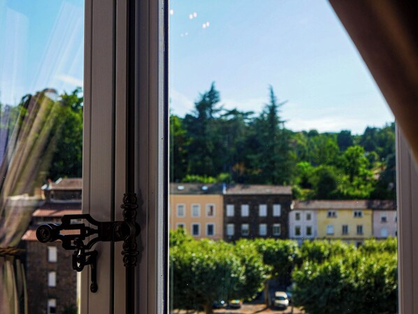 A window with a view of a cityscape, including buildings and greenery.