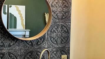A bathroom with a round mirror, a sink, and decorative tiles.