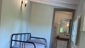 A bedroom with a bed, a bedside table, a lamp, and a view into the bathroom. - B&B CIVICO 33 (Scalea)
