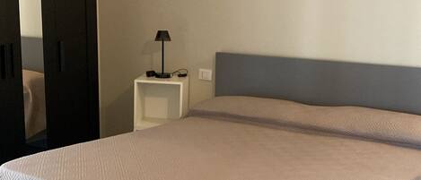 Un dormitorio moderno con cama, mesita de noche y espejo.