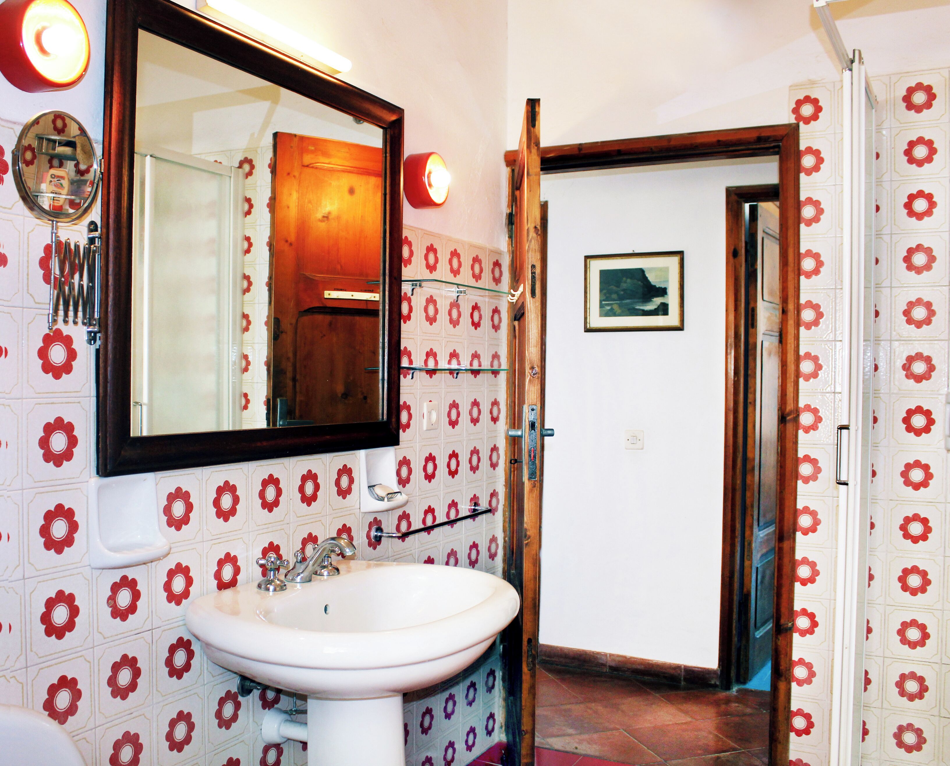 Un baño con un lavamanos blanco, un espejo y una puerta de madera.