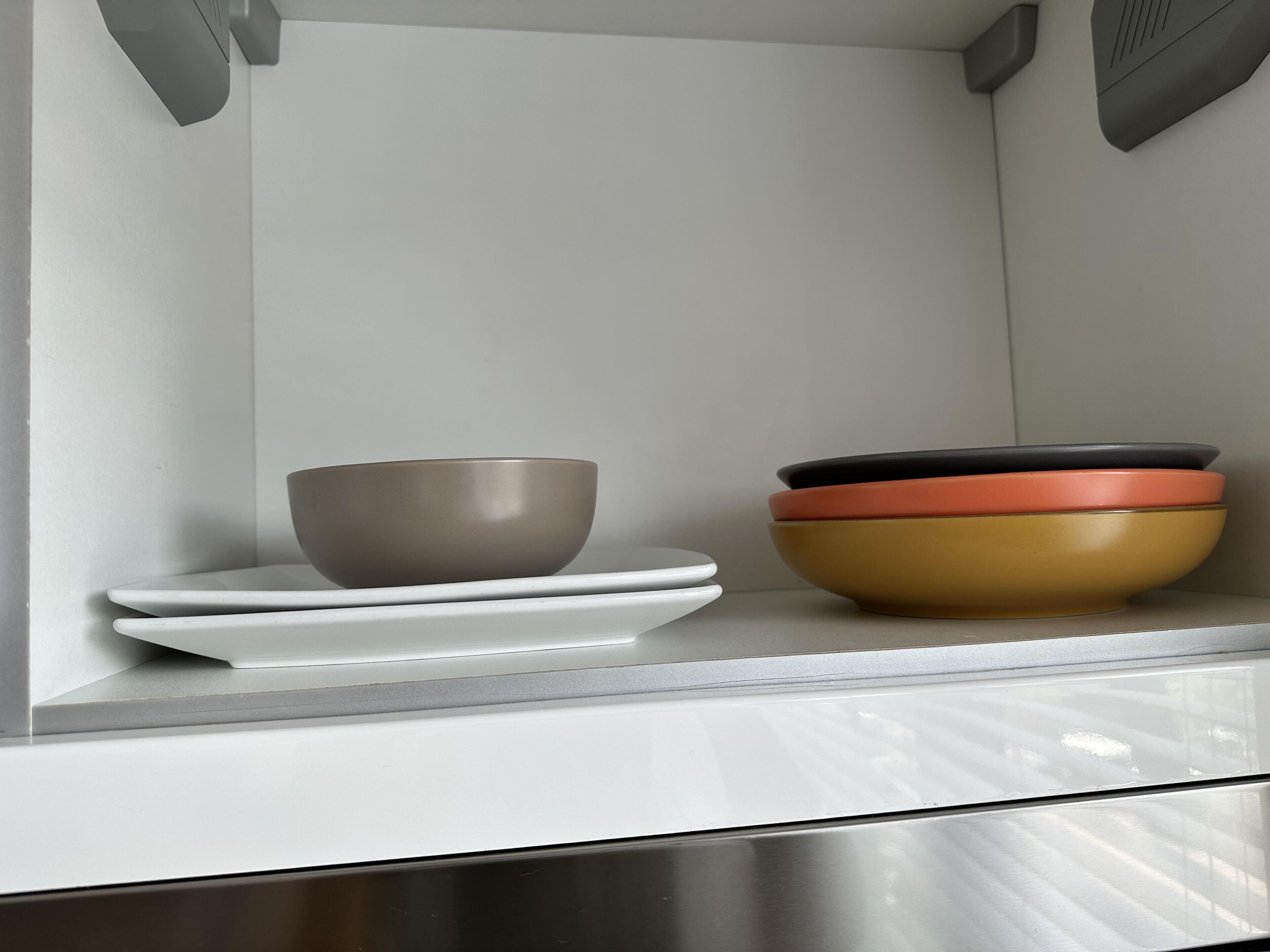 A kitchen counter with a bowl, plates, and a stack of bowls.