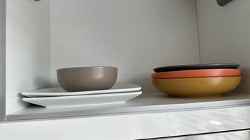 A kitchen counter with a bowl, plates, and a stack of bowls.
