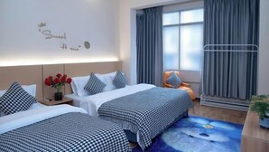 Une chambre d’hôtel avec deux lits, une table de chevet ornée d’un vase de roses rouges, une fenêtre avec des rideaux et un mur décoré d’un panneau.