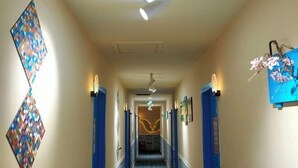 Un couloir d'hôtel avec un décor mural à motifs, un ventilateur de plafond et un élément décoratif mural.