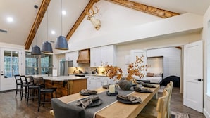 Un'ampia cucina con un'isola centrale allungata, travi in legno a soffitto e una testa di cervo appesa al muro.