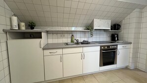 Eine moderne Küche mit weißen Schränken, einer Edelstahl-Spüle und einem eingebauten Backofen.