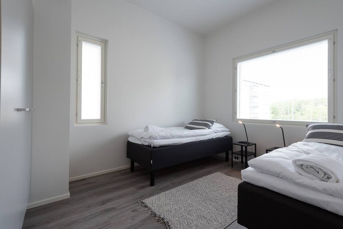 Ein Schlafzimmer mit Bett, Nachttisch, Fenster und Tür.
