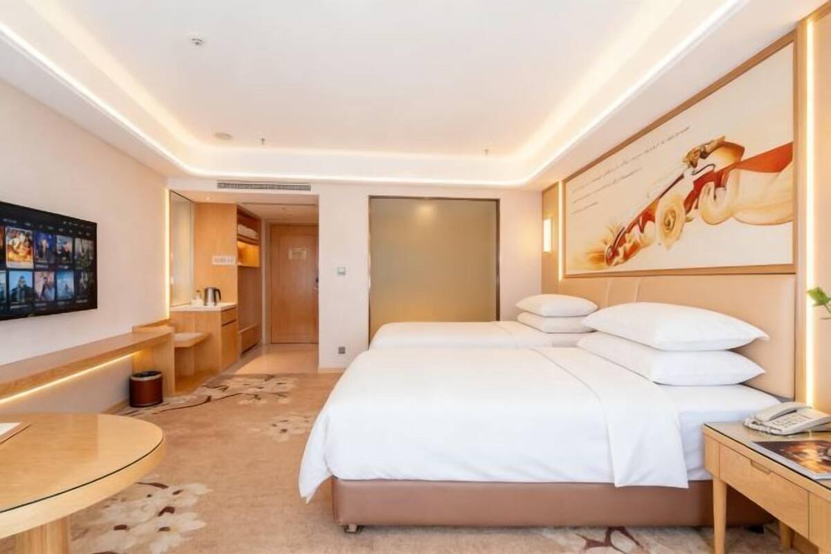 A modern hotel room with a bed, bedside table, and a wall-mounted TV.