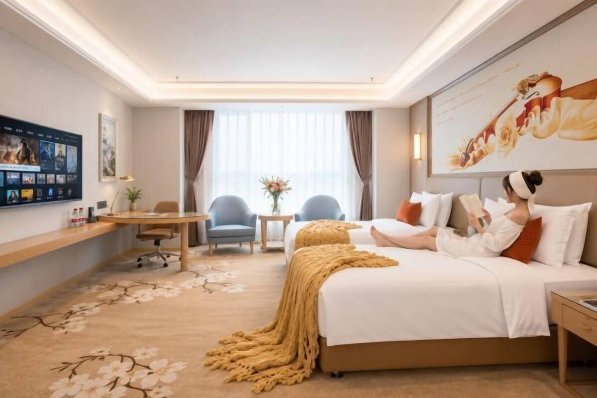 A hotel room with a bed, a desk, a chair, a TV, and a large window.