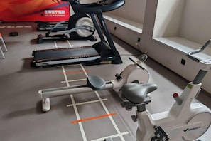 A gym with exercise equipment including treadmills, an elliptical, and a stationary bike. - Vienna Hotel (Foshan West Railway Station Airport Branch) (Foshan)