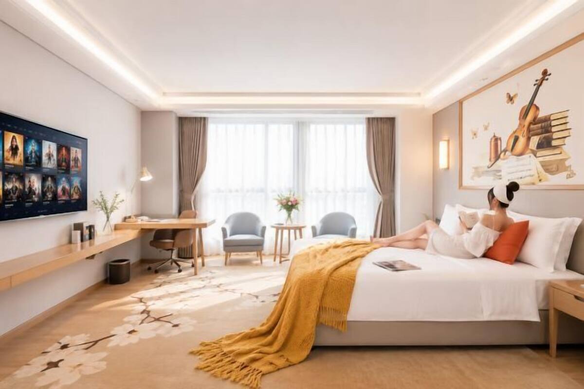 A hotel room with a bed, a desk, a chair, a small table, and a window.