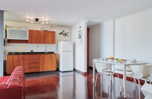 Une cuisine moderne avec des meubles en bois, un réfrigérateur blanc et un coin repas comprenant des chaises et une table blanches.