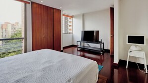 Ein Schlafzimmer mit einem großen Bett, einem Fernseher auf einem Schrank und einer Schiebetür, die auf einen Balkon führt.