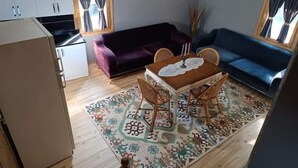 A compact living space with a dining area, two sofas, a kitchen, and a patterned rug. - DIAMOND TREE HOUSE (Maçka)