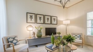 A modern living room with a sofa, a coffee table, a TV, and framed artwork on the wall. - Egidio City Farmhouse (Lucca)