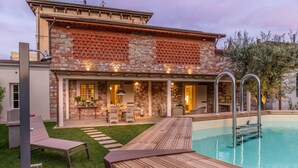 A modern house with a swimming pool, outdoor seating area, and a well-maintained lawn. - Egidio City Farmhouse (Lucca)