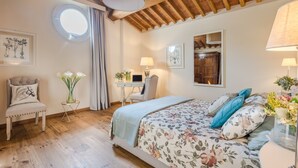 A bedroom with a bed, a desk, a chair, and a round window. - Egidio City Farmhouse (Lucca)