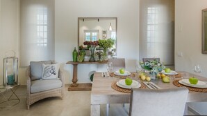 A dining area with a wooden table set for four, surrounded by wicker chairs. - Egidio City Farmhouse (Lucca)