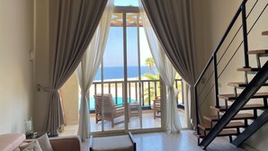 A room with a large window, a staircase, and a view of the ocean.