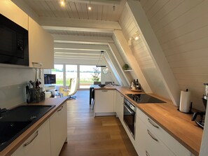 Een moderne keuken met een houten aanrecht, een inbouwoven en een groot raam met uitzicht op de omgeving.