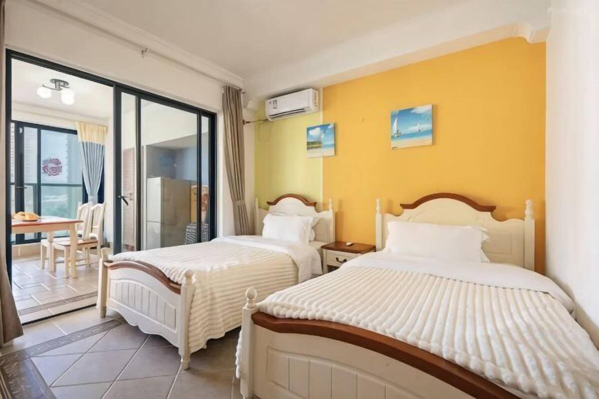 Habitación de hotel con dos camas, un rincón de comedor y puerta corrediza de cristal al exterior.