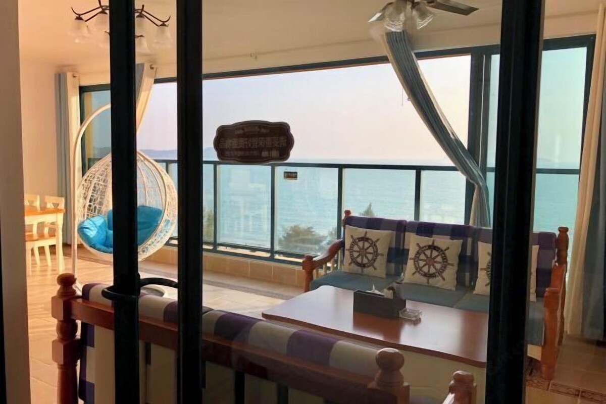 Ein Balkon mit Meerblick, einem Hängesessel und einer Couch mit Kissen im Marine-Stil.