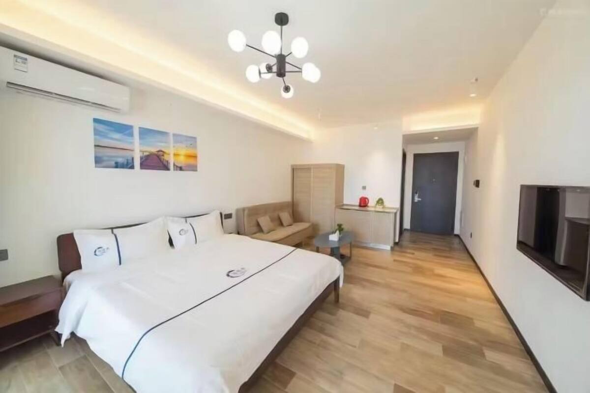Una habitación de hotel moderna con una cama grande, un sofá, un televisor y una pequeña mesa.