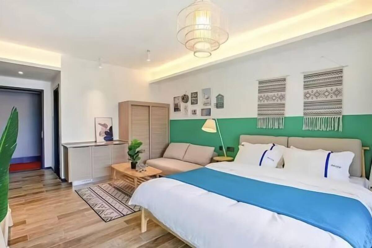 Un dormitorio moderno con cama, mesita de noche, lámpara y una pared de acento verde.