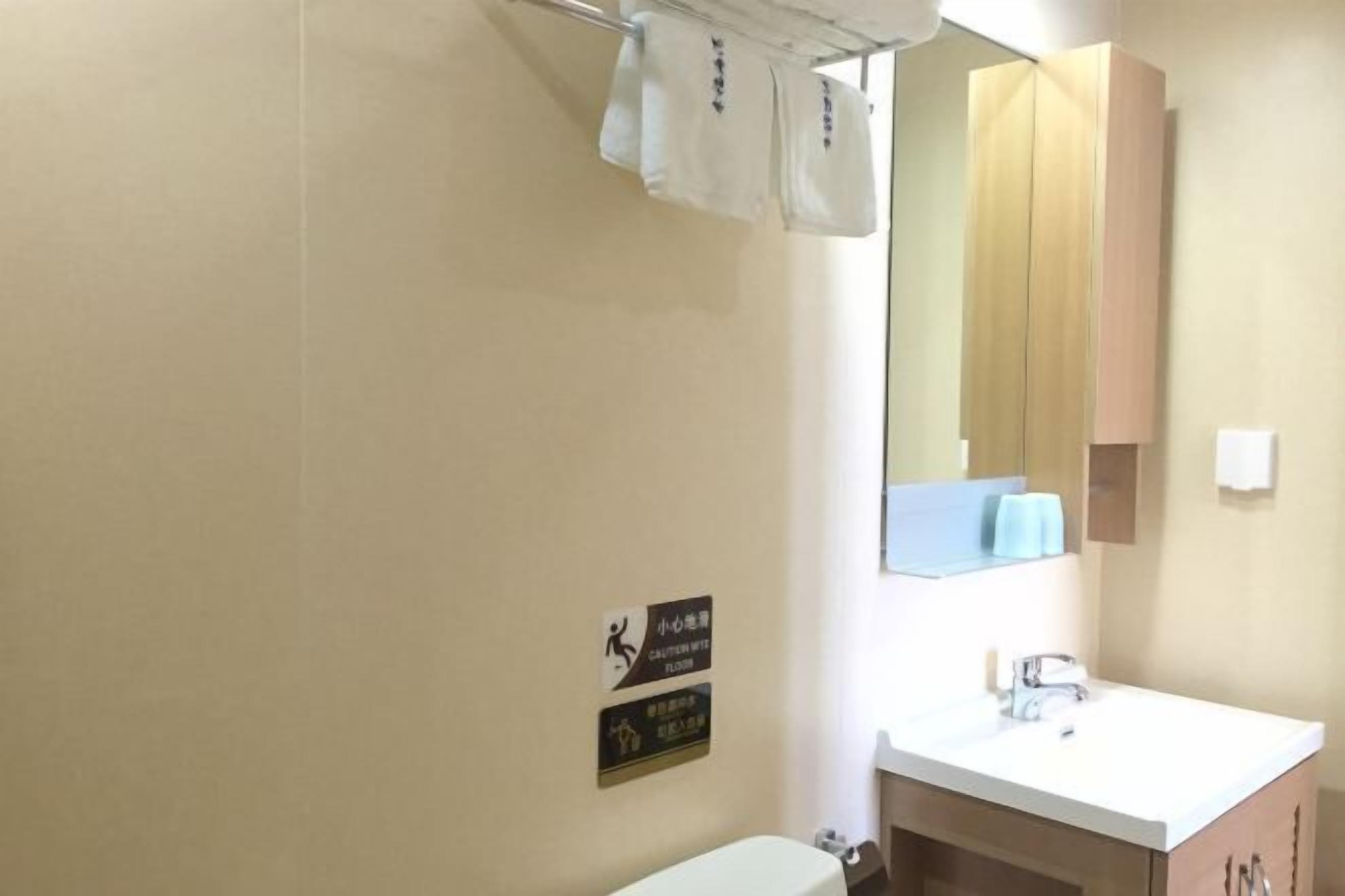 A bathroom with a white sink, a mirror, and a towel rack. There are signs on the wall indicating the location of the bathroom and the floor level.