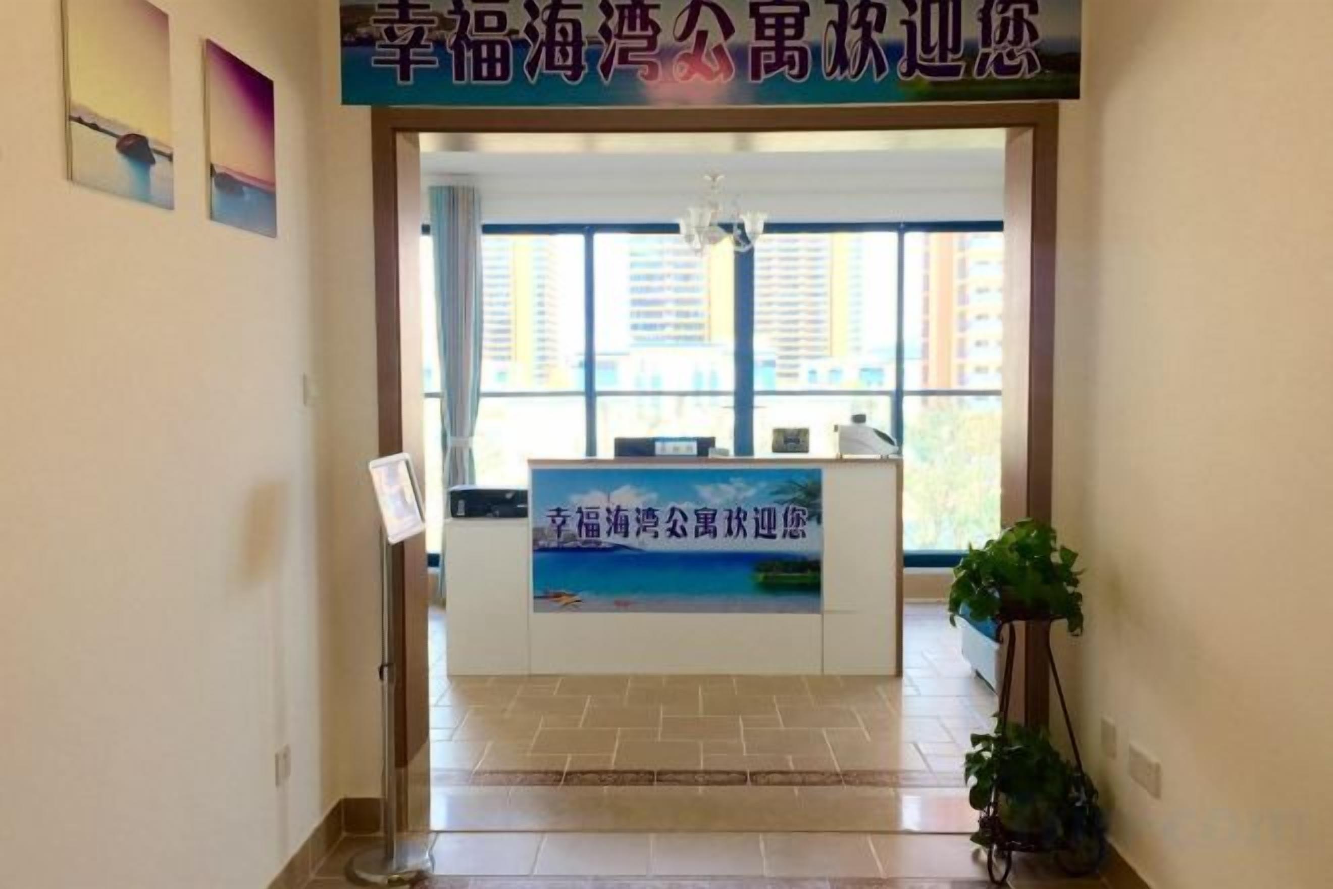 A reception area with a reception desk, a signboard, and a potted plant.