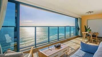 Un balcón con vista al mar, un comedor y un sofá.