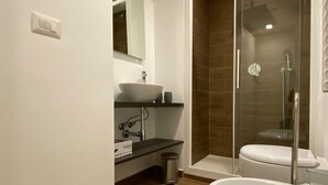 Une salle de bain moderne avec un grand lavabo blanc, une douche à parois de verre et des toilettes.