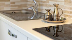 A kitchen sink with a modern faucet and a tray holding two metallic containers. - Casa Clara Uri in the Nuraghe of Santa Cadrina a short distance from the beaches (Uri)