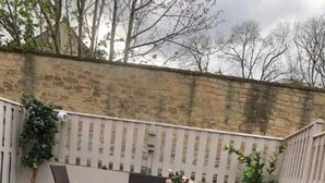 A backyard with a white fence, a small table with chairs, and a potted plant. - Stunning 3-bed House in Bristol (Bristol)