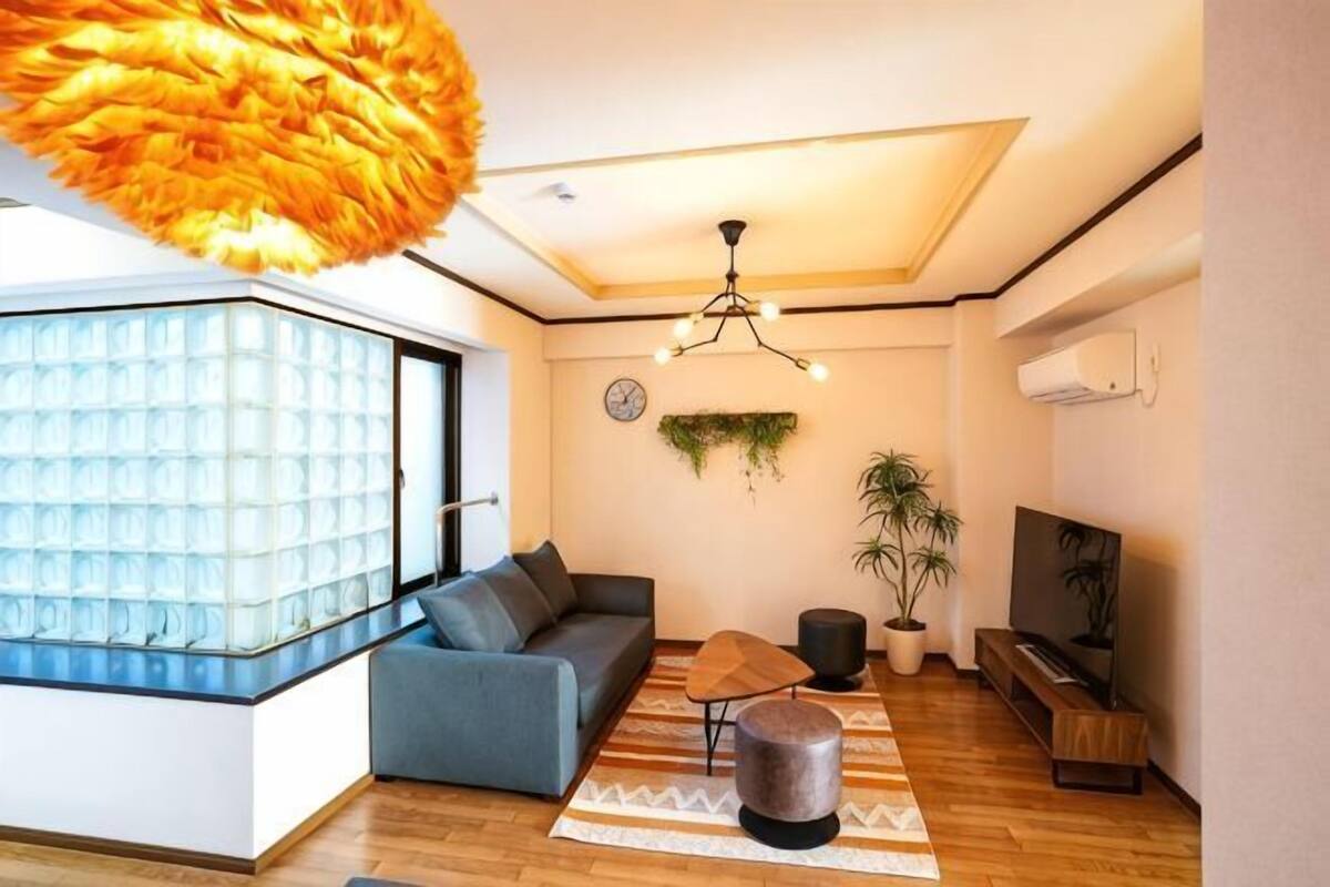 A modern living room with a sofa, a coffee table, a TV, and a large window.