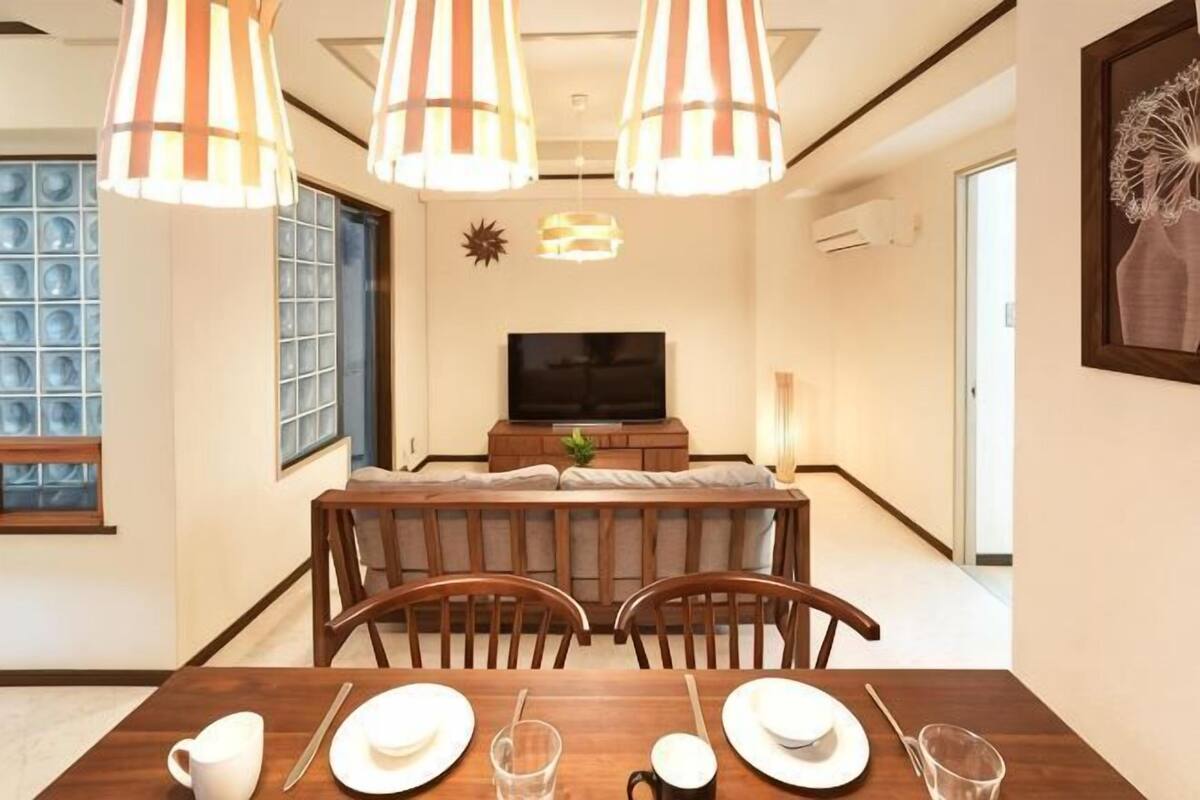 A dining area with a wooden table, chairs, and hanging lamps.
