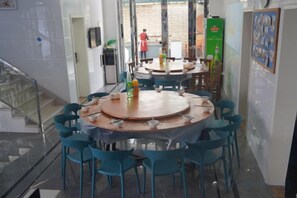 A dining area with round tables and blue chairs, a staircase, and a view of the outside. - Tianchen Villa (Shengsi)