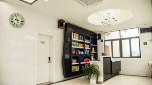 A modern reception area with a white door, a bookshelf filled with various items, a potted plant, and a chandelier. - Tianchen Villa (Shengsi)