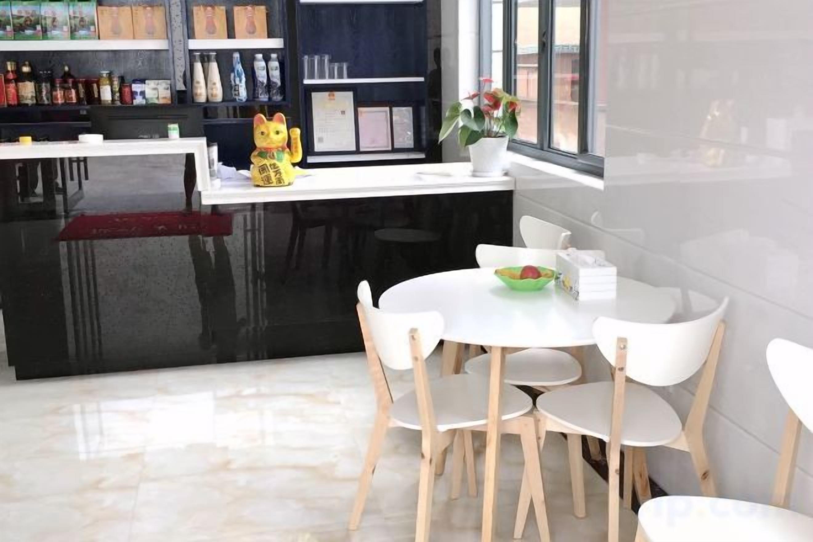 A modern kitchen with a black countertop, white chairs, and a dining table.