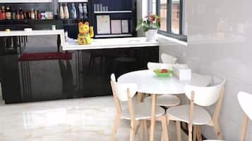 A modern kitchen with a black countertop, white chairs, and a dining table.