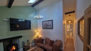 A living room with a fireplace, a sofa, a coffee table, and a television. - High Spec 1-bed Cottage in Staindrop, Darlington (Darlington)
