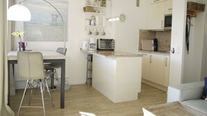 Eine moderne Küche mit weißen Schränken, einer zentralen Kochinsel und einem Essbereich mit Tisch und Stühlen.