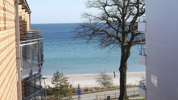 Blick auf einen Strand von einem Gebäude mit einem Balkon, der auf das Meer hinausgeht.