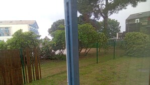 A fenced outdoor area with grass and trees. - Au Port,agreable Appartement de Plain Pied Avec Terrasse (Hourtin)
