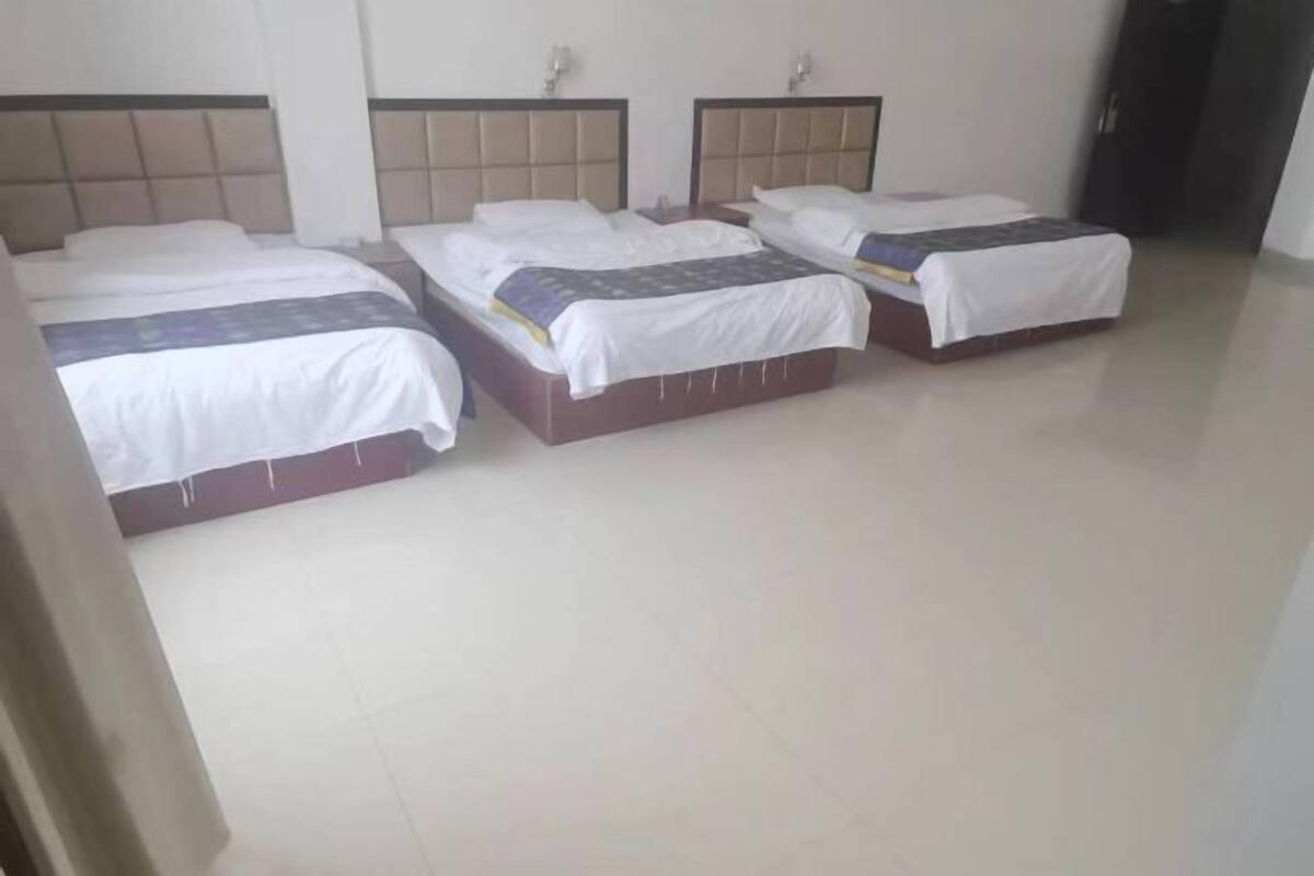 A hotel room with three beds, each with a headboard and white bedding.